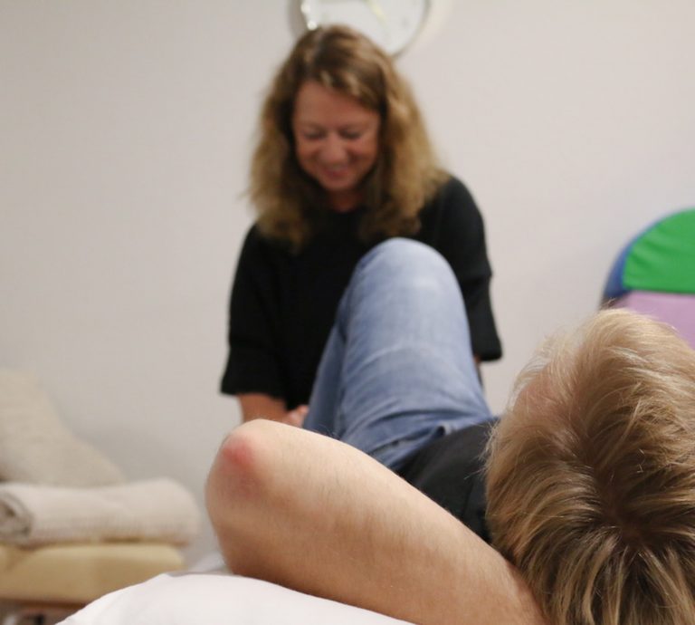 Doris Godt behandelt einen erwachsenen Patienten auf einer Liege in ihrer Physiotherapiepraxis